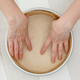 Hands lining round cake pan with parchment paper for baking